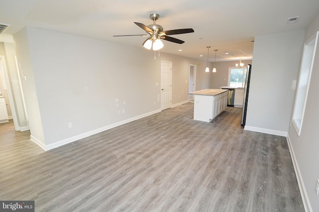 unfurnished living room featuring hardwood / wood-style flooring and ceiling fan with notable chandelier