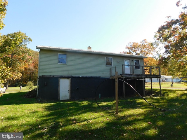 back of property with a deck and a lawn