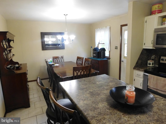 kitchen with backsplash, white cabinetry, stainless steel appliances, pendant lighting, and an inviting chandelier