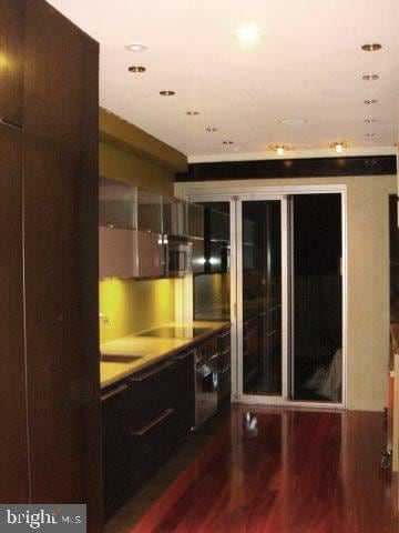 bar with stainless steel oven, black cooktop, and hardwood / wood-style flooring