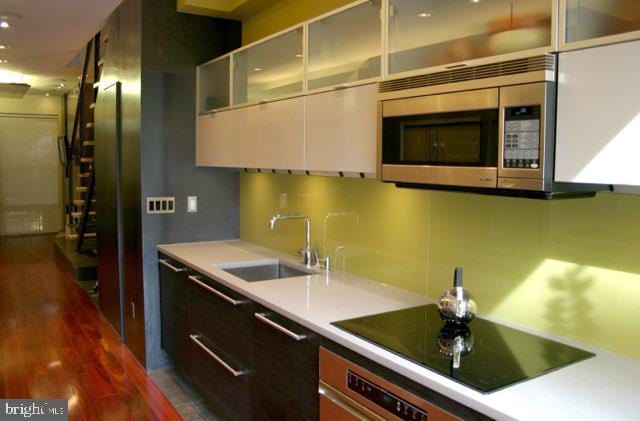 kitchen with dark hardwood / wood-style floors, decorative backsplash, sink, and black electric stovetop