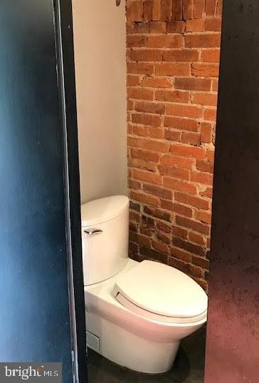 bathroom with brick wall and toilet