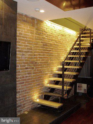 staircase featuring brick wall