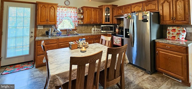 kitchen with a wealth of natural light, sink, decorative backsplash, and stainless steel appliances