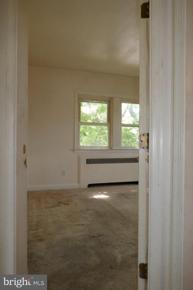 carpeted spare room featuring radiator