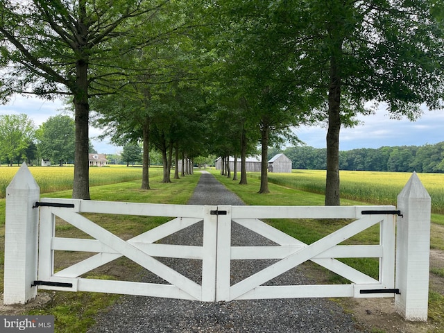 view of gate featuring a rural view and a lawn