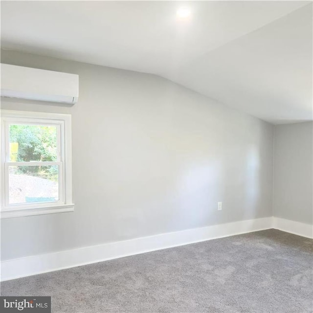 carpeted spare room with a wall mounted AC and vaulted ceiling