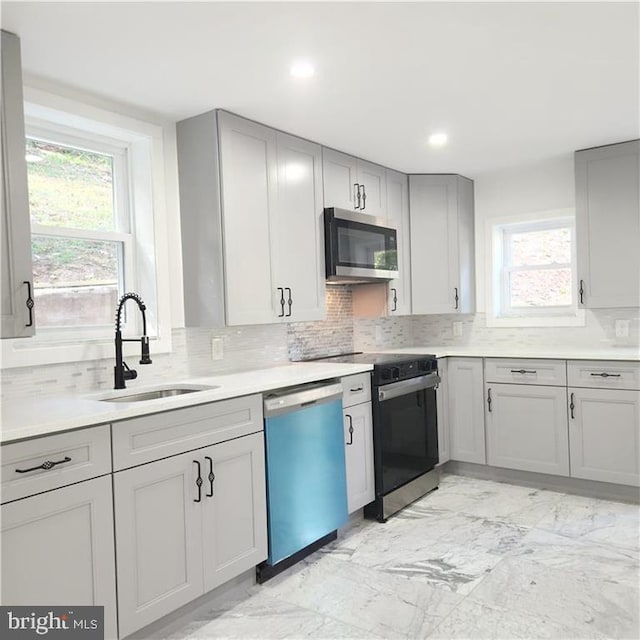 kitchen featuring appliances with stainless steel finishes, decorative backsplash, a healthy amount of sunlight, and sink