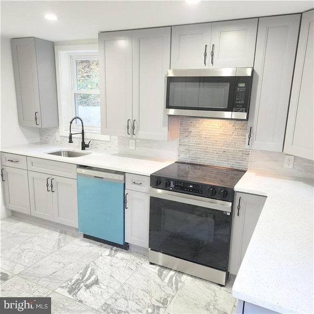 kitchen featuring gray cabinetry, appliances with stainless steel finishes, sink, and decorative backsplash