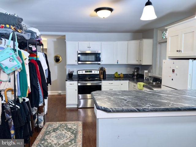 kitchen with kitchen peninsula, dark hardwood / wood-style flooring, white cabinetry, and appliances with stainless steel finishes