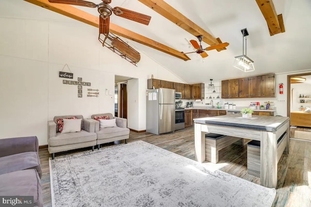 kitchen featuring appliances with stainless steel finishes, beam ceiling, high vaulted ceiling, and hardwood / wood-style flooring