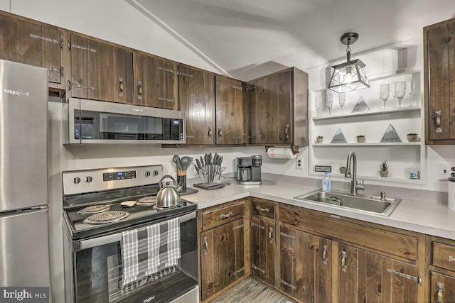 kitchen featuring lofted ceiling, dark brown cabinets, stainless steel appliances, sink, and pendant lighting