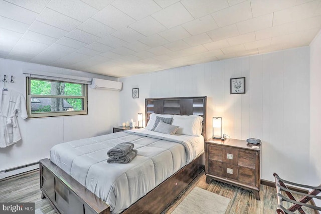 bedroom featuring light hardwood / wood-style flooring, a wall mounted AC, and a baseboard radiator