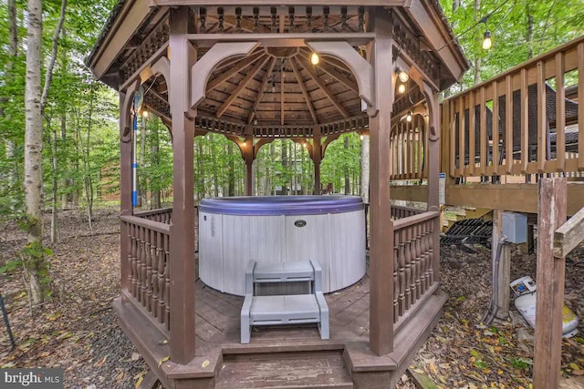 wooden deck with a hot tub and a gazebo