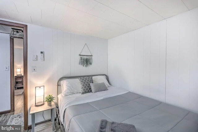 bedroom with hardwood / wood-style flooring and wooden walls