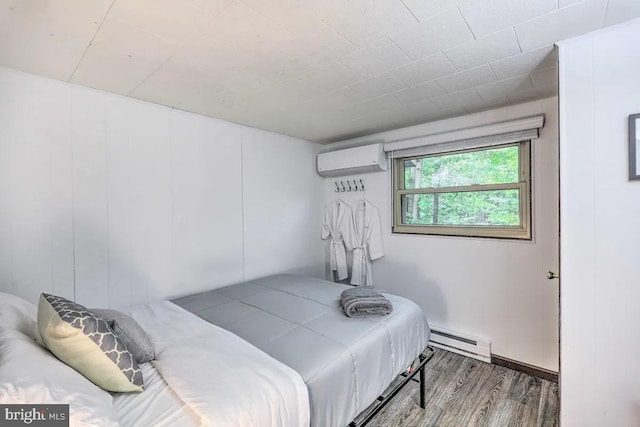 bedroom with a wall mounted air conditioner, baseboard heating, and hardwood / wood-style flooring