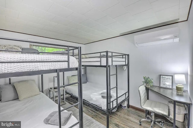 bedroom with hardwood / wood-style flooring and a wall mounted air conditioner