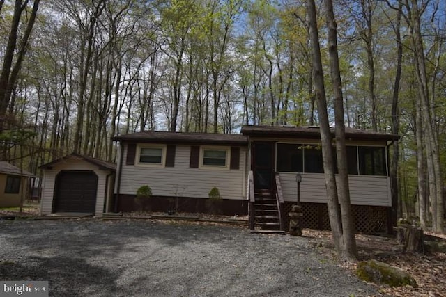 view of front facade with a sunroom, a garage, and an outdoor structure