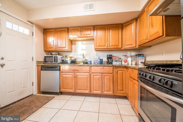 kitchen with extractor fan, dark stone counters, stainless steel appliances, and light tile patterned floors