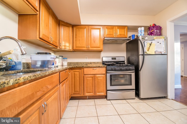 kitchen featuring dark stone countertops, light tile patterned floors, appliances with stainless steel finishes, and sink