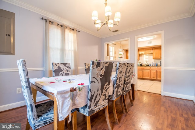 dining room featuring an inviting chandelier, light hardwood / wood-style flooring, electric panel, and crown molding