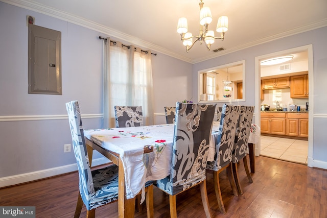 dining room with an inviting chandelier, light hardwood / wood-style flooring, electric panel, and crown molding