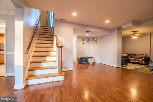 stairs with ceiling fan, wood-type flooring, and ornamental molding