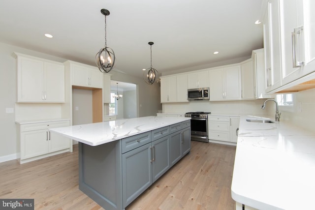 kitchen featuring white cabinets, stainless steel appliances, gray cabinets, a center island, and light hardwood / wood-style floors