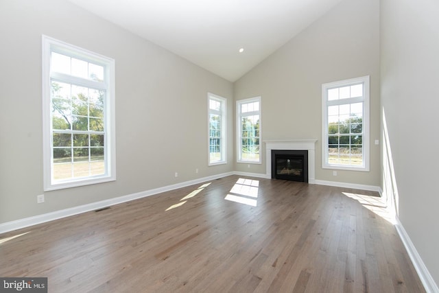 unfurnished living room with high vaulted ceiling and light wood-type flooring