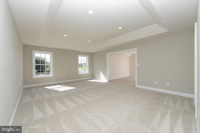 carpeted empty room with a tray ceiling