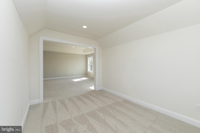 carpeted empty room with vaulted ceiling