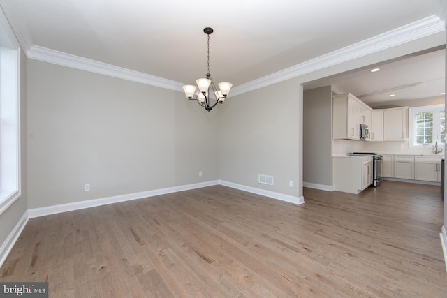 interior space with light hardwood / wood-style flooring, ornamental molding, and a notable chandelier