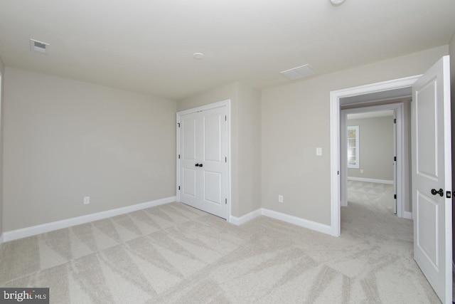 unfurnished bedroom with a closet and light colored carpet