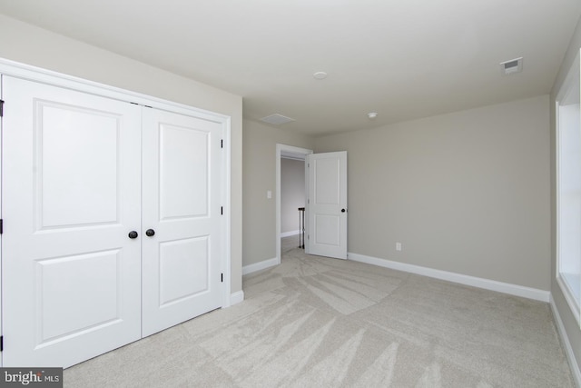 unfurnished bedroom featuring light colored carpet and a closet