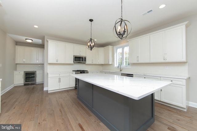 kitchen with stainless steel appliances, wine cooler, a center island, light wood-type flooring, and white cabinets