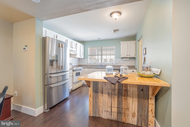 kitchen featuring electric stove, sink, decorative backsplash, stainless steel fridge, and white cabinetry