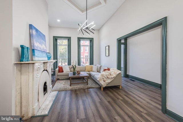 living room with high vaulted ceiling, a fireplace, wood-type flooring, and an inviting chandelier