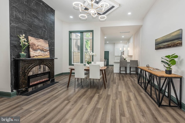 dining area with a notable chandelier, a fireplace, and wood-type flooring