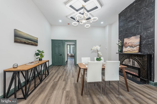 dining space with a high end fireplace, a chandelier, and wood-type flooring