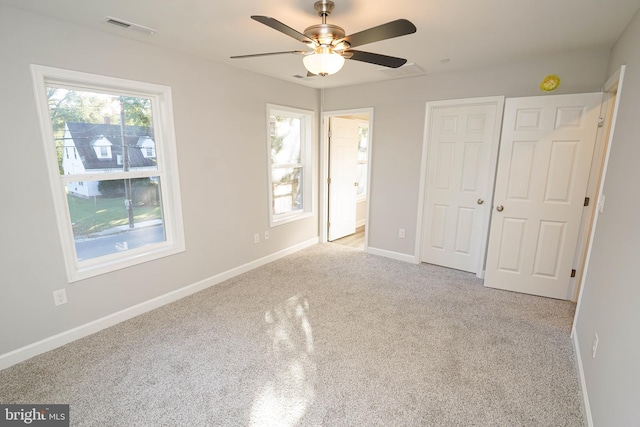 unfurnished bedroom featuring light carpet, ensuite bathroom, and ceiling fan