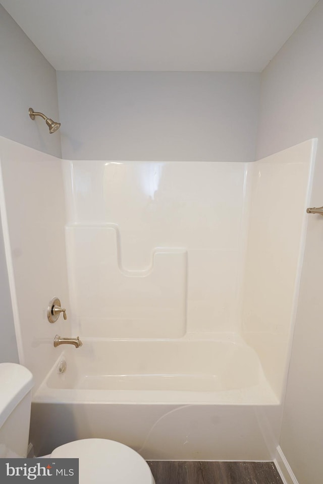 bathroom featuring shower / bathing tub combination, hardwood / wood-style flooring, and toilet