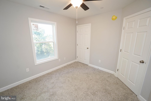 carpeted empty room featuring a skylight and ceiling fan