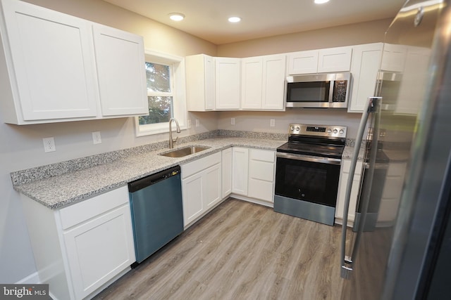 kitchen with sink, white cabinetry, light hardwood / wood-style flooring, and stainless steel appliances