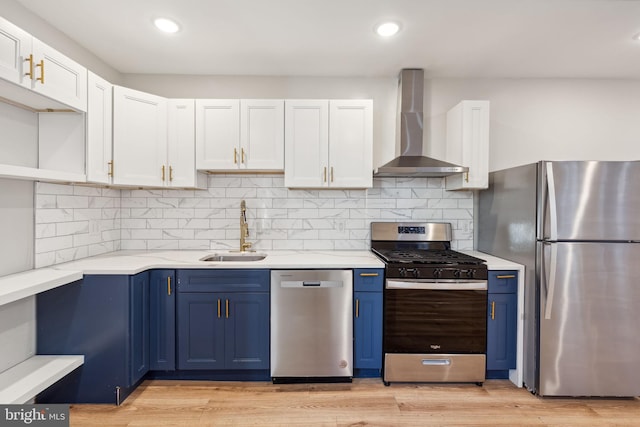 kitchen featuring light wood-type flooring, stainless steel appliances, wall chimney range hood, and blue cabinets