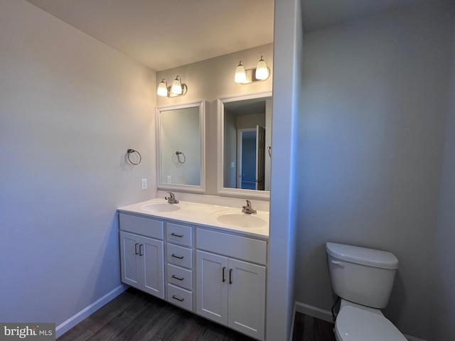 bathroom featuring a sink, toilet, wood finished floors, and double vanity