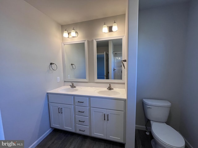 full bathroom featuring double vanity, toilet, baseboards, and a sink