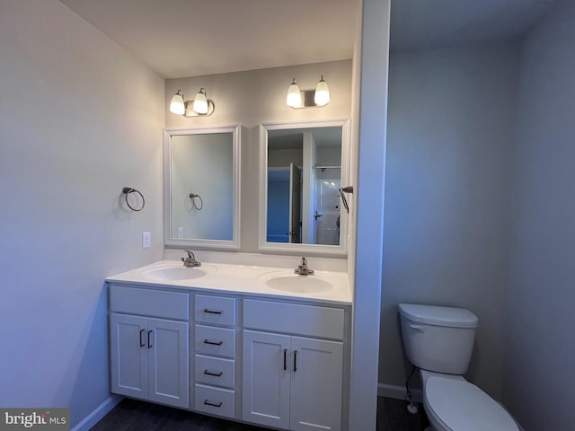 full bath with a sink, baseboards, toilet, and double vanity