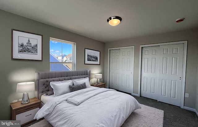 bedroom with baseboards, multiple closets, and dark carpet