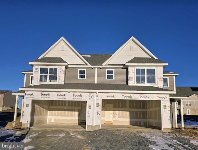 unfinished property featuring an attached garage and a shingled roof