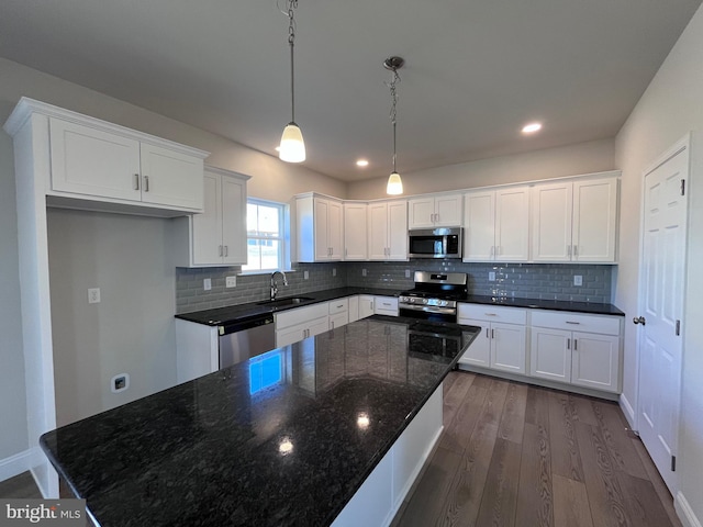 kitchen with a sink, tasteful backsplash, dark wood finished floors, white cabinetry, and appliances with stainless steel finishes